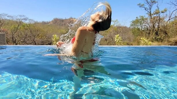 A person swimming in a clear blue pool with a natural landscape in the background. - Baliyana Lodge (Pinilla)