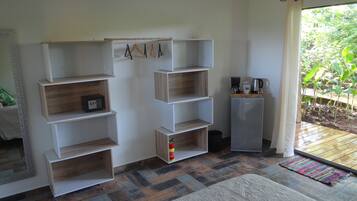 Una habitación con una estantería empotrada de madera, un refrigerador pequeño y una cafetera sobre una encimera.