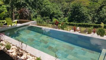 Una piscina al aire libre, sombrillas, tumbonas