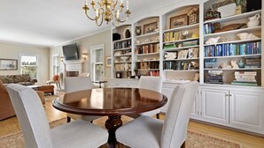 Un coin repas avec une table ronde et des chaises, entouré d’étagères remplies de livres et d’objets décoratifs.