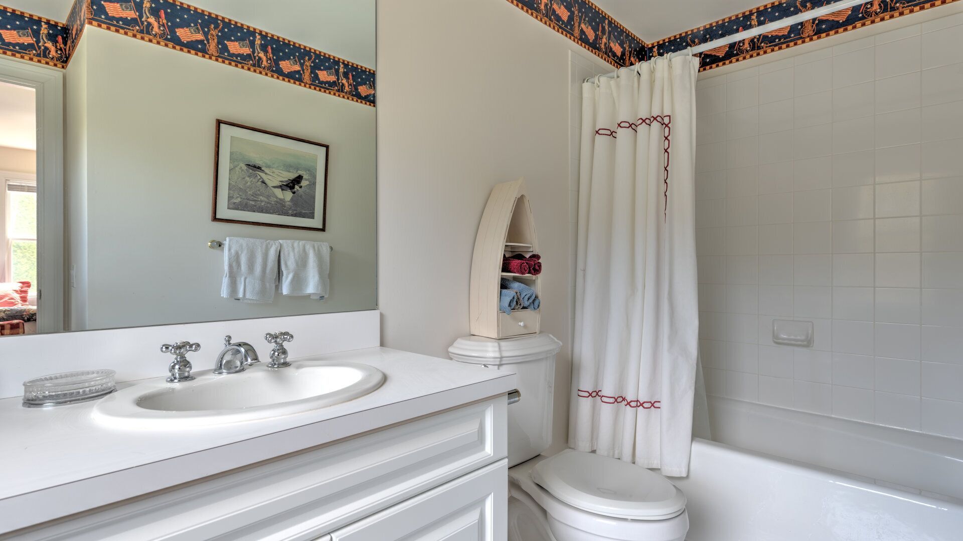 A bathroom with a white sink, mirror, and toilet, a shower curtain, and a towel rack with towels.