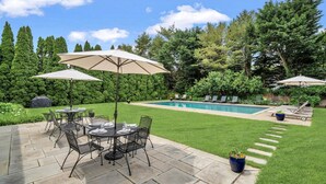 Un jardin avec une piscine, des meubles de patio et une pelouse bien entretenue.