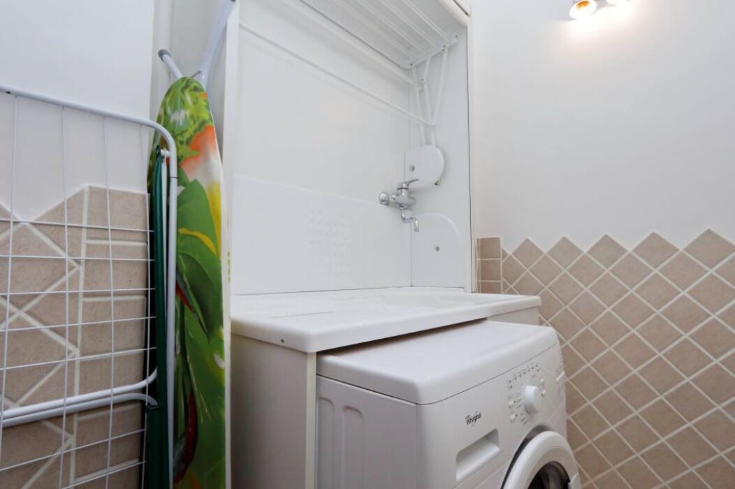 A compact bathroom with a washing machine, a shower, and a toilet.