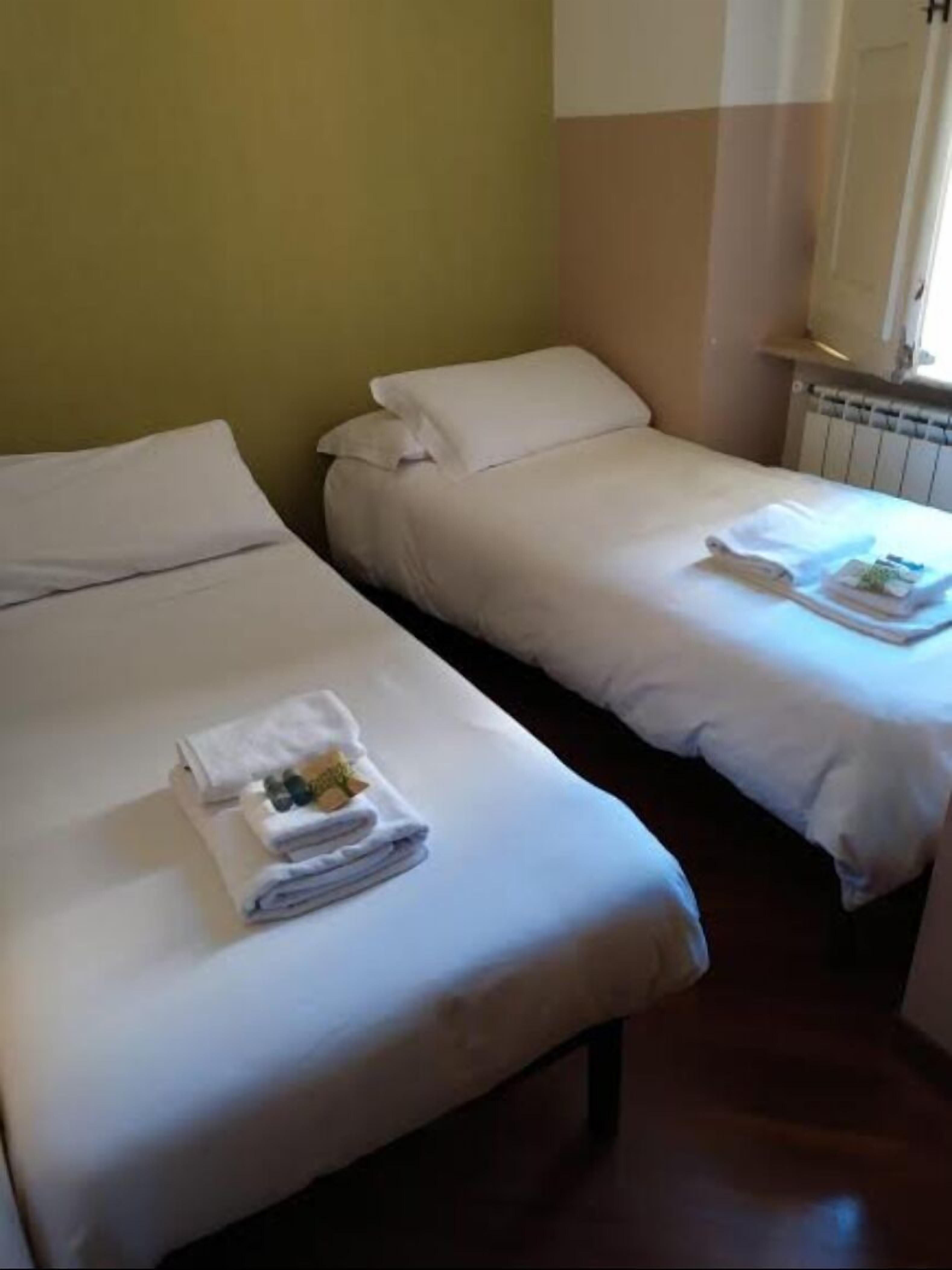 Two single beds with white linens and folded towels on each bed.
