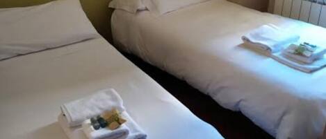 Two single beds with white linens and folded towels on each bed.