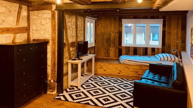 A cozy bedroom with a bed, a dresser, a TV on a small table, and a window with curtains. - Hausele holiday apartment (Sulzbach an der Murr)