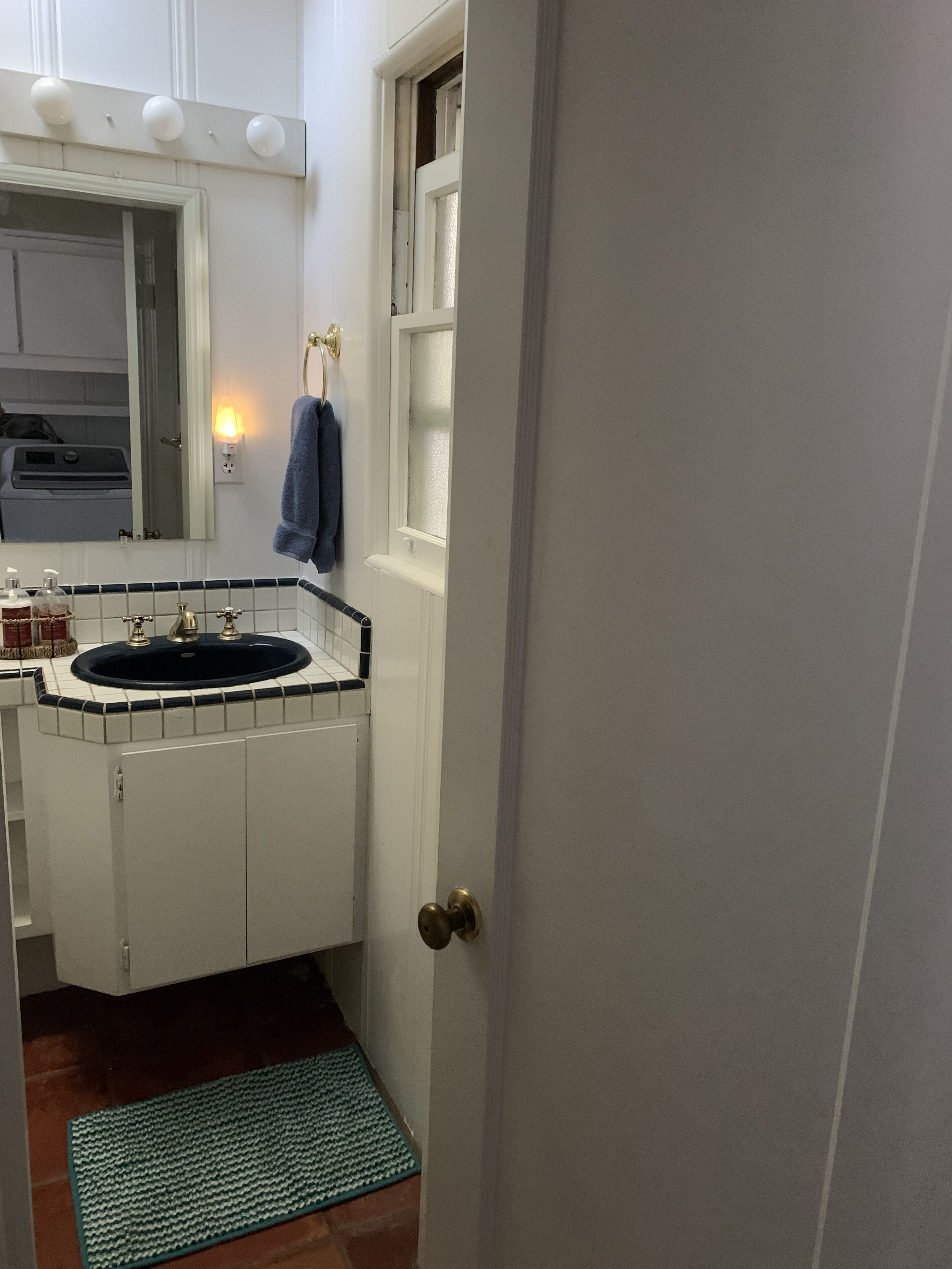 A bathroom with a white sink, a mirror, and a window.
