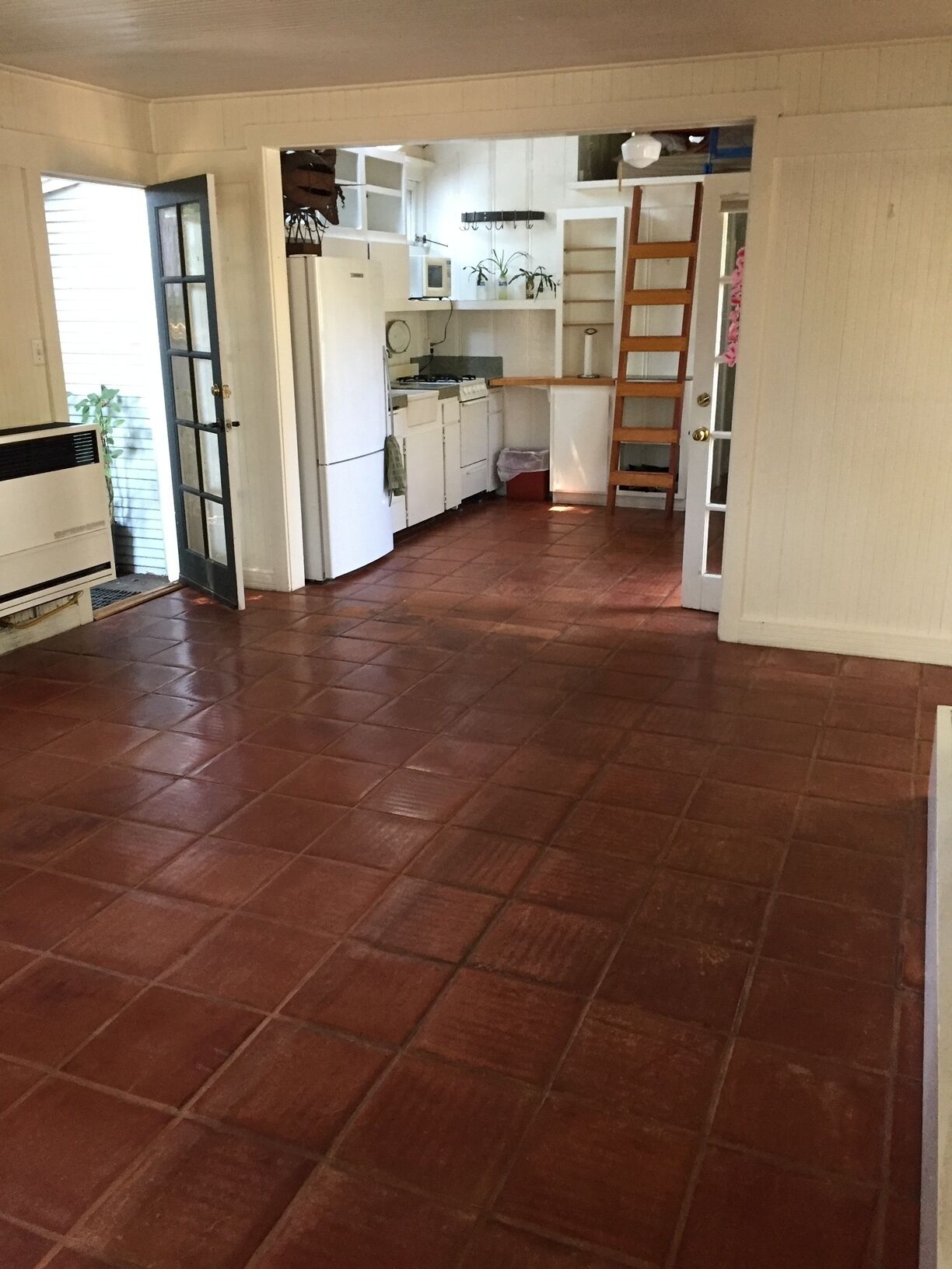 A spacious kitchen with white cabinets, a stove, and a microwave.
