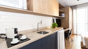 Una cocina moderna con microondas integrado, cafetera y lavamanos.