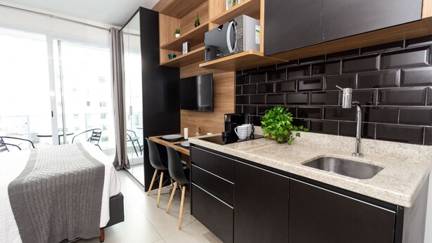 Una cocina moderna con armarios negros, encimera de granito y microondas integrado.