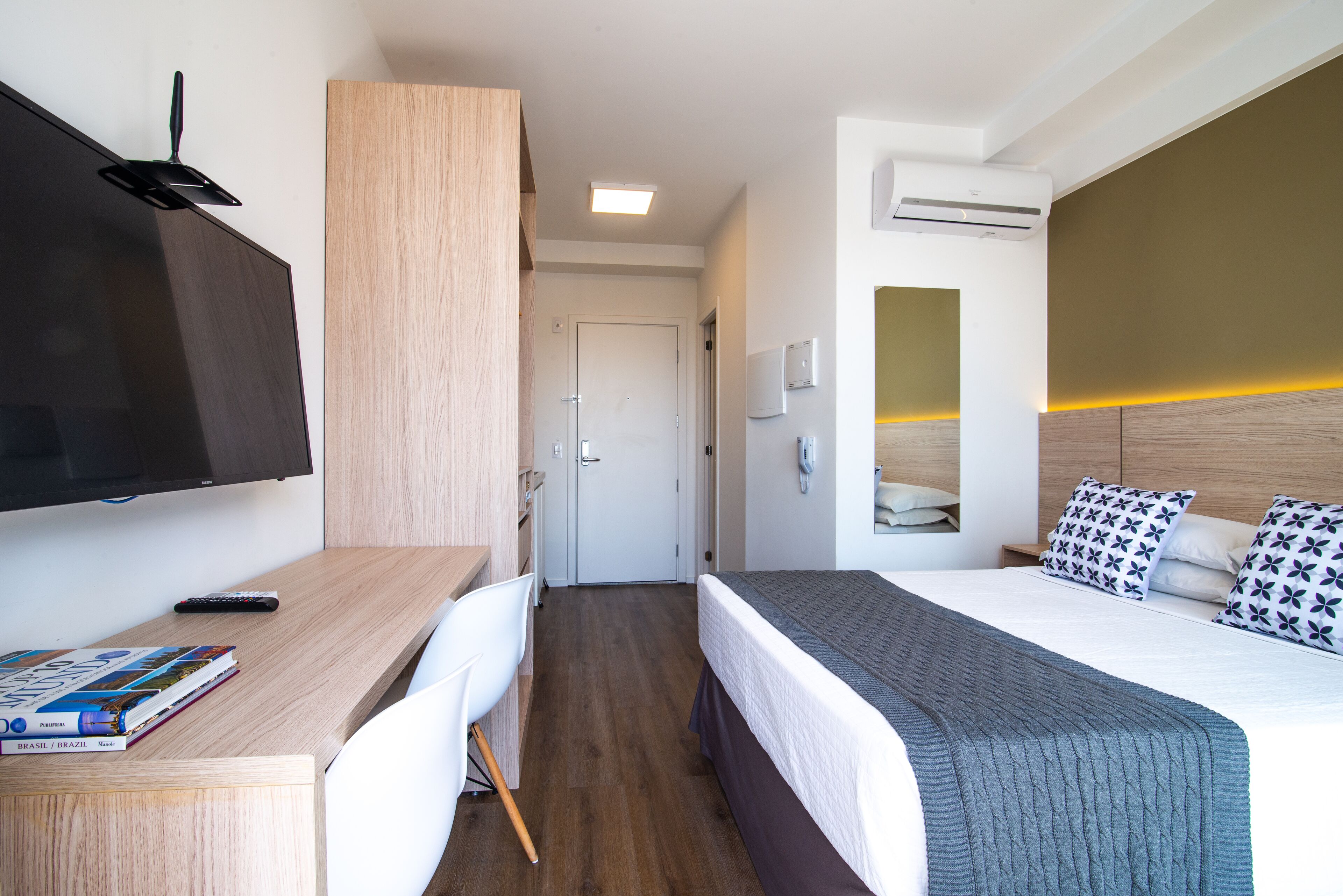 Habitació d'hotel amb un llit, escriptori, cadira, televisió i aire condicionat.