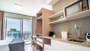 Una cocina moderna con microondas integrado, un lavabo y ventana con vistas a un paisaje urbano.