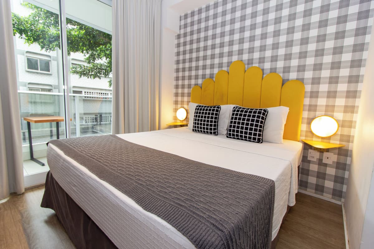 A hotel room with a large bed, checkered wallpaper, and two bedside lamps.