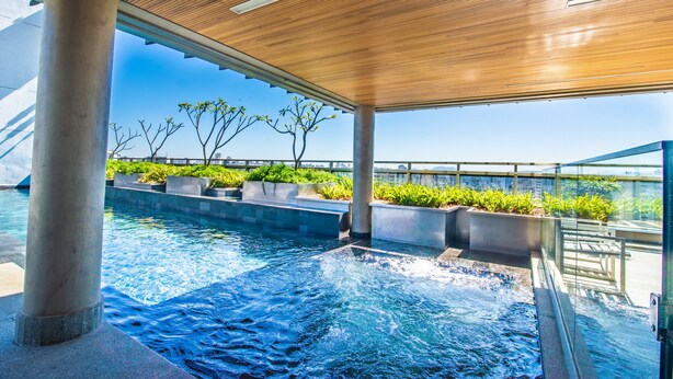 A rooftop infinity pool with a wooden ceiling, concrete pillars, and planters with greenery. - 360 República (São Paulo)