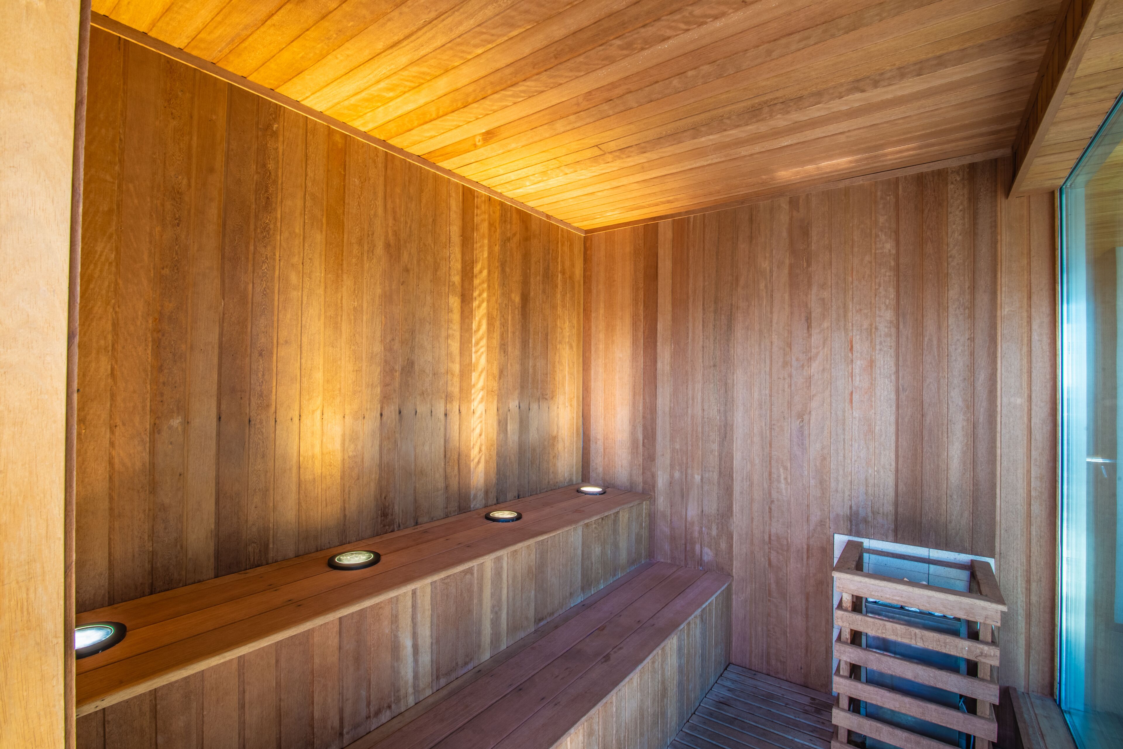 A wooden sauna with benches and a wooden bench at the end.