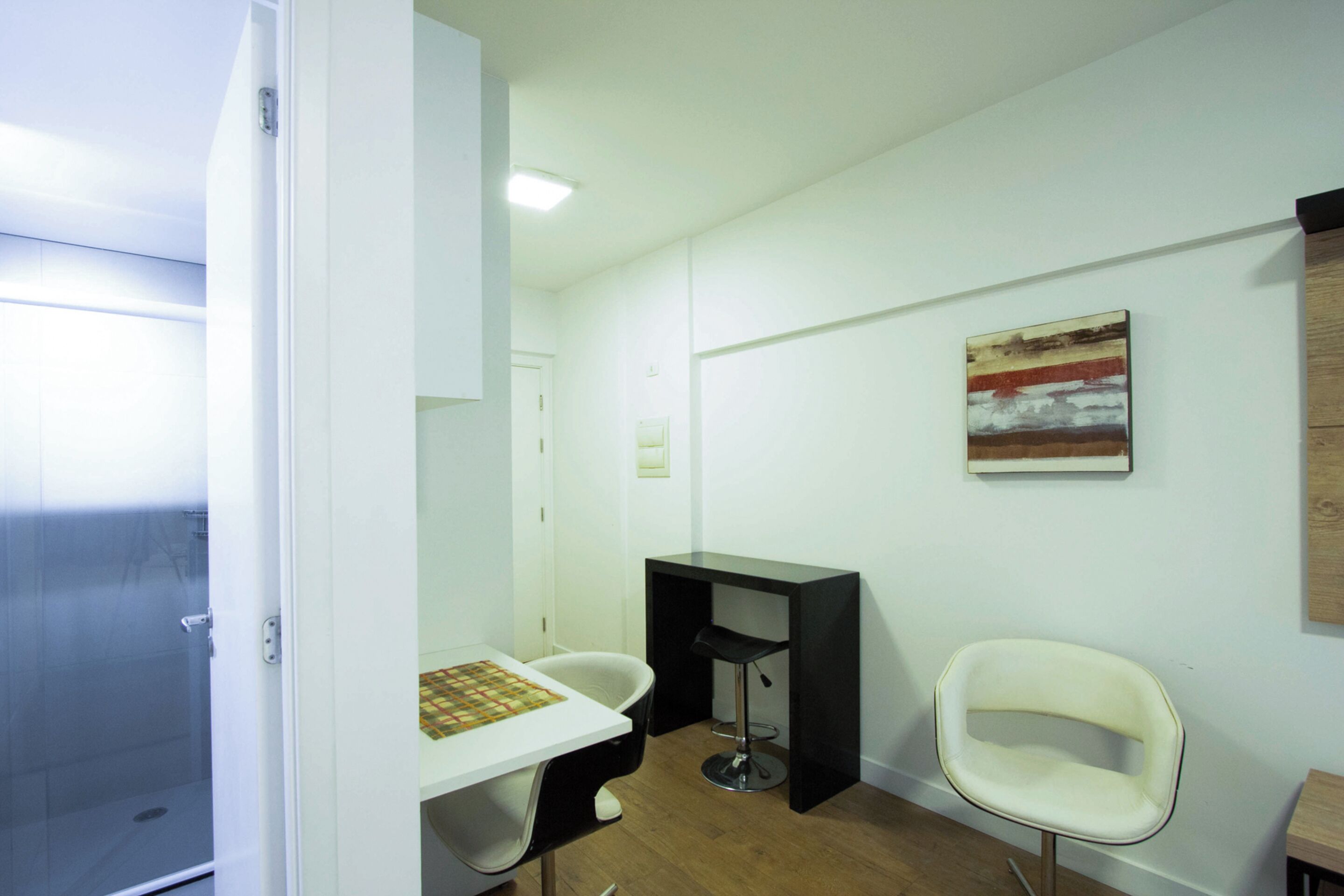 Une salle de bain avec une douche, un lavabo, un miroir et une petite table sur laquelle est posée une serviette.
