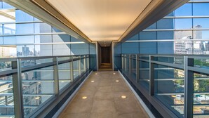 A corridor with glass railings and a view of the cityscape. - 360 República (São Paulo)