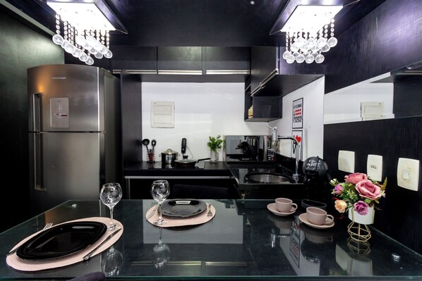 Una cocina moderna con electrodomésticos de acero inoxidable, una mesa de comedor de vidrio y un florero con flores.