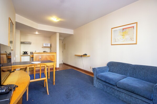 A compact living space with a kitchenette, a dining area, and a blue sofa. - 360 Santa Cecília (São Paulo)