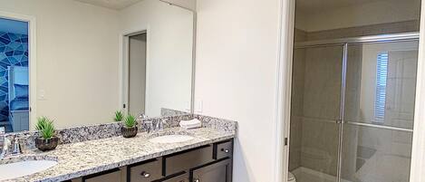 A modern bathroom with a large vanity, a shower enclosure, and a blue rug.