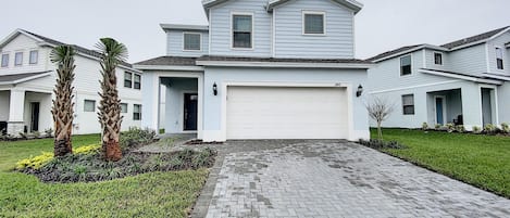 A two-story house with a garage, a driveway, and a well-maintained lawn.
