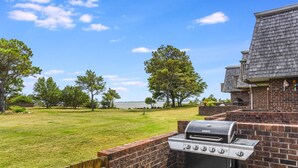 Ein Grillbereich im Freien mit Grill, Backsteinmauer und Seeblick.