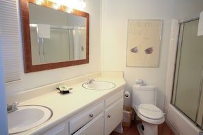 Une salle de bain avec deux lavabos, des toilettes et une douche.