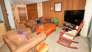 A living room with a brown sofa, a wooden coffee table, a rocking chair, and a television. - Sierra Park Villas #82 (Mammoth Lakes)