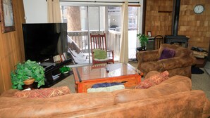 A living room with a sofa, a glass-top coffee table, a television, and a fireplace. - Sierra Park Villas #82 (Mammoth Lakes)