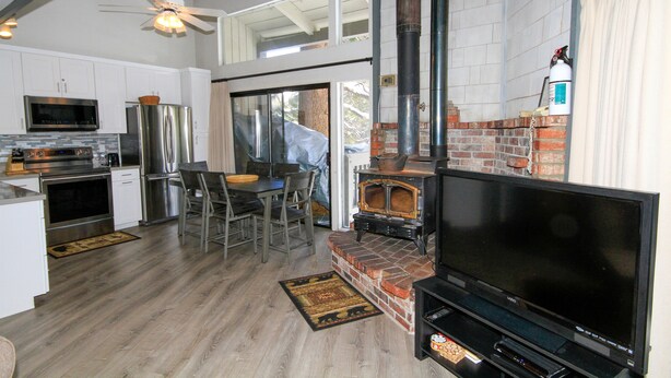 A modern kitchen with stainless steel appliances, a dining area with a table and chairs, and a large TV in a living area. - Sierra Park Villas #93 (Mammoth Lakes)