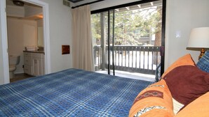 A bedroom with a bed, a bathroom, and a balcony with a view. - Sierra Park Villas #93 (Mammoth Lakes)