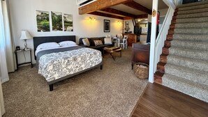 Une chambre dotée d’un grand lit, d’un canapé, d’un coin repas et d’un escalier menant à un niveau supérieur.