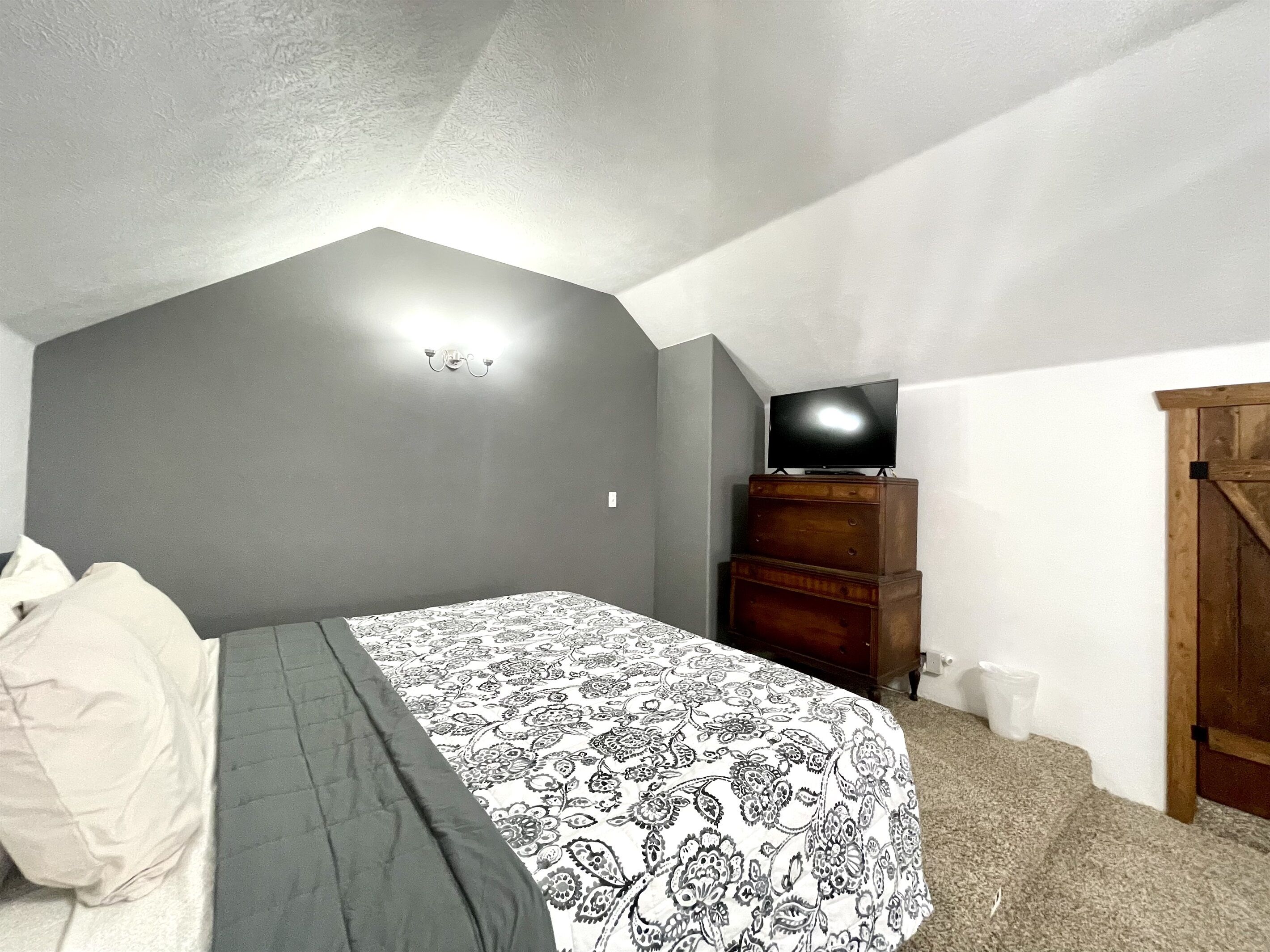 Um quarto com cama, cômoda e televisão.