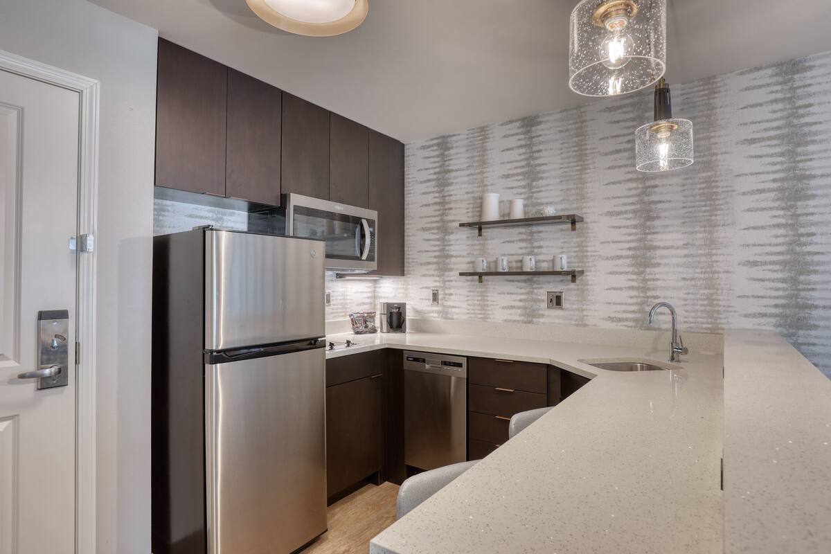 A modern kitchen with stainless steel appliances, a dishwasher, and a white countertop.