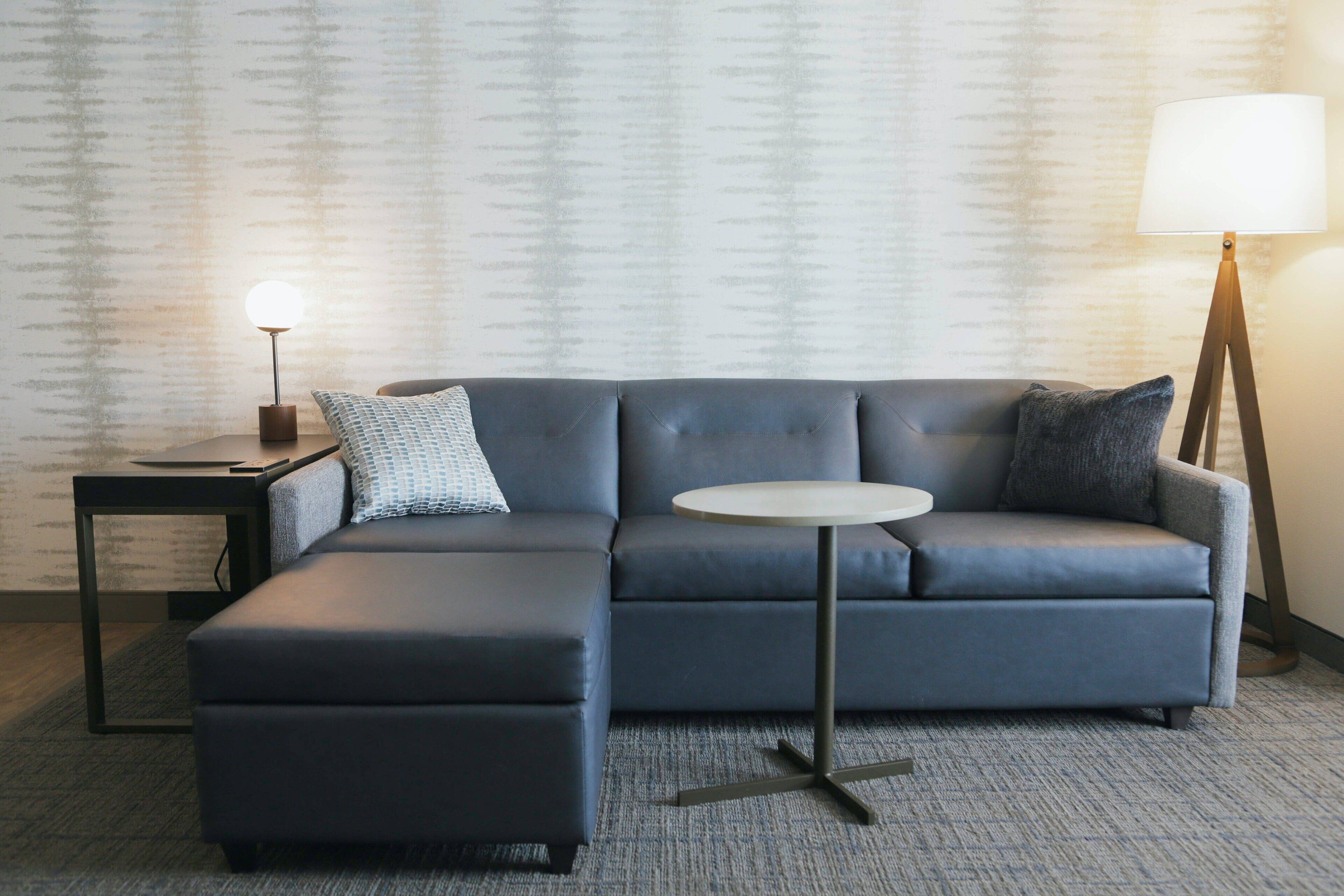 A modern living room with a grey sectional sofa, a round coffee table, and a lamp.