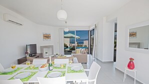 Ein moderner Essbereich mit Meerblick, einem Pool und einem Balkon.