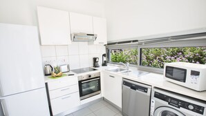Eine moderne Küche mit weißen Schränken, einem Backofen, einer Spülmaschine und einer Mikrowelle.