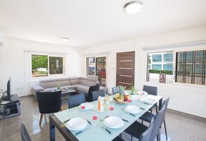 Un coin repas avec une table dressée pour quatre personnes, un canapé et un téléviseur dans un coin.