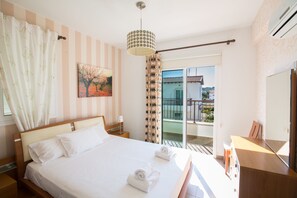 Ein Hotelzimmer mit einem großen Bett, einem Gemälde, Blick auf den Balkon und einem Holztisch.