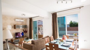 Een moderne woonkamer met een bank, televisie en eethoek.