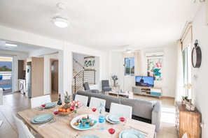 A modern living room with a dining area, a sofa, and a television. - Villa Elli, Charming 3BDR Pernera Villa with Pool, Walking Distance to Beach (Pernera)