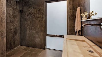 A bathroom with a shower, a sink, and a towel rack.