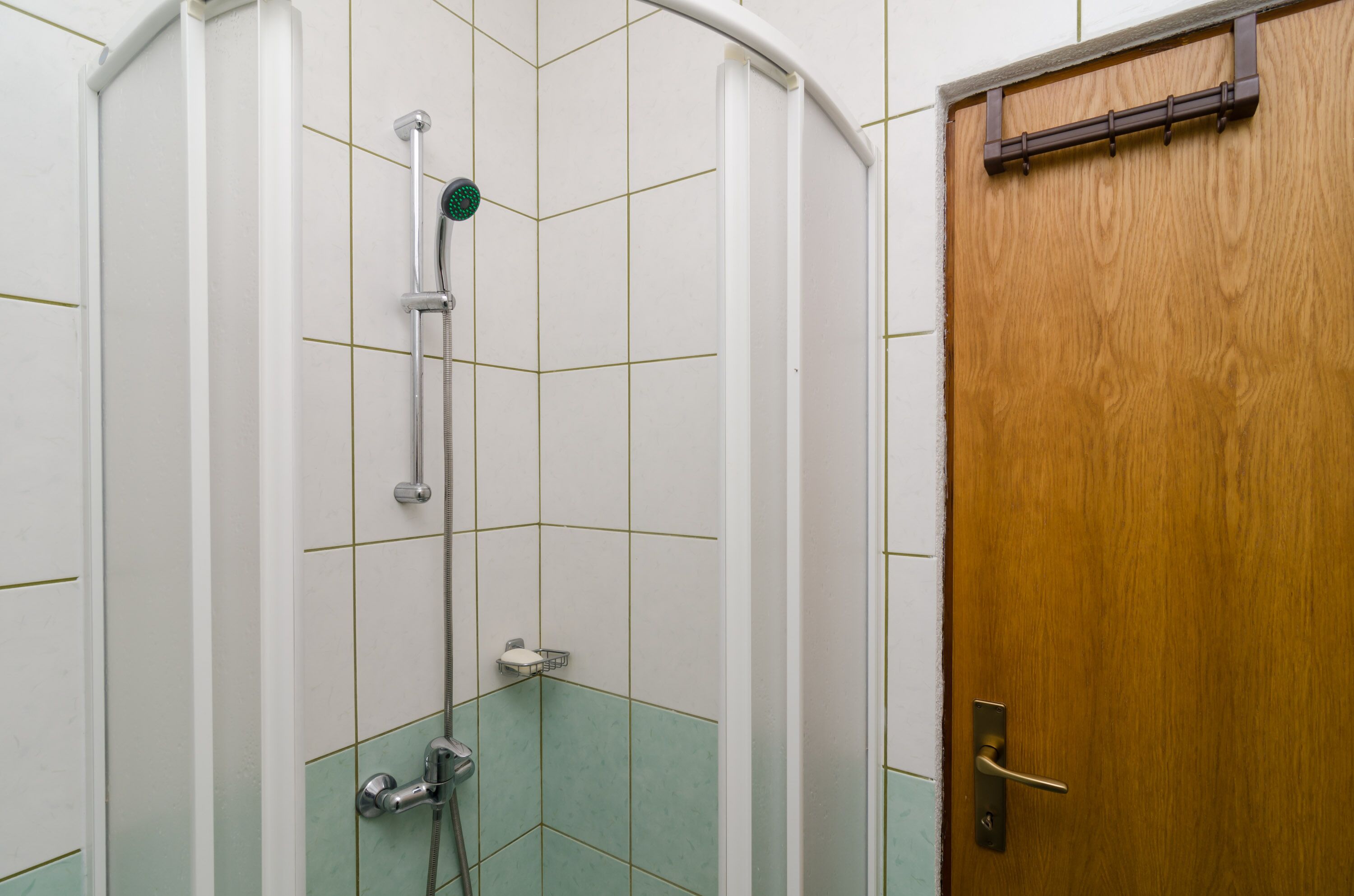 A shower with a handheld showerhead and a wall-mounted faucet.