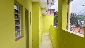 Un couloir étroit aux murs jaunes et au sol carrelé, qui mène à une porte au fond.