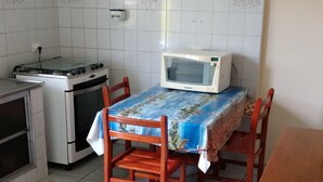 Une petite cuisine équipée d’une cuisinière à gaz, d’un four à micro-ondes et d’une table avec des chaises.