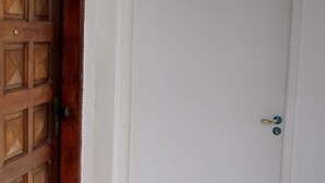 Une porte blanche fermée, ornée d’un panneau en bois et dotée d’un trou de serrure.