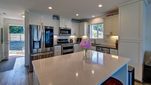 A modern kitchen with stainless steel appliances, white cabinetry, and a large island. - Hood Canal waterfront five bedrooms hottub watercrafts boat launch Olympic view (Belfair)