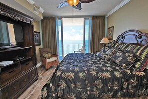 A hotel room with a large bed, a television, a chair, and a balcony with a view of the ocean. - San Carlos 1001 (Gulf Shores)