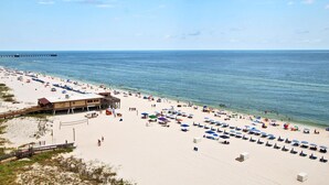 A beach with a lifeguard tower, umbrellas, and beach chairs. - San Carlos 1001 (Gulf Shores)