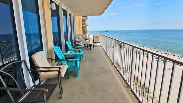 A balcony with turquoise chairs and a table, overlooking a beach with a clear view of the ocean. - San Carlos 1001 (Gulf Shores)